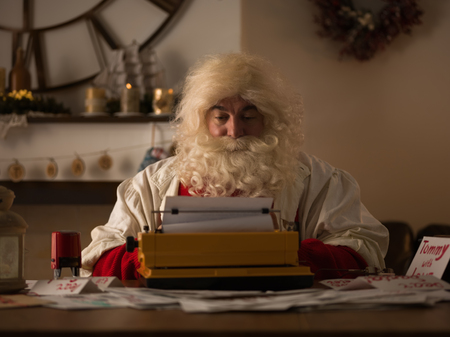 Santa Claus Working at Home. Reading and Writing letters for Children on Typewriterの写真素材
