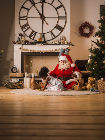 Santa Claus playing with cute african american Child at Homeの写真素材