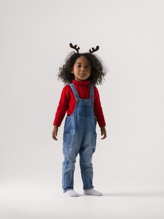 African little girl wearing reindeer horns full length Portrait on plain backgroundの写真素材