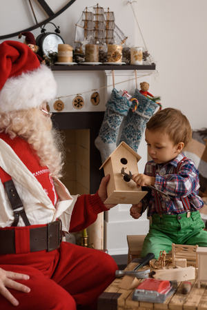 Santa Claus with Child making Christmas Gifts and Toys at Homeの写真素材