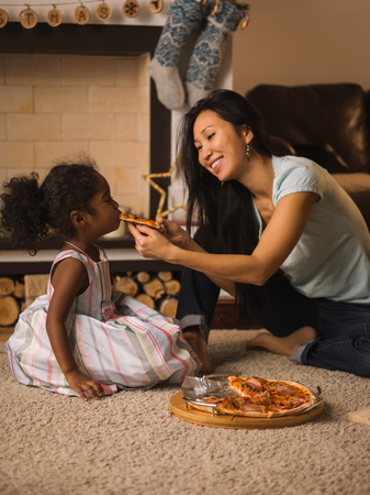Mother and Daughter eating pizza at homeの写真素材