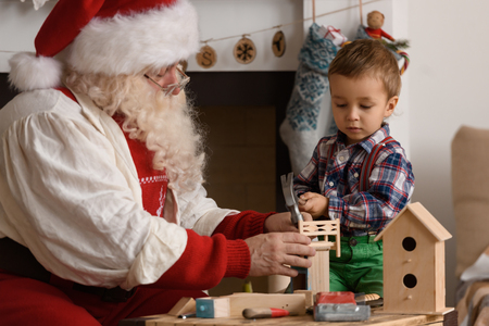 Santa Claus with Child making Christmas Gifts and Toys at Homeの写真素材