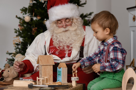 Santa Claus with Child making Christmas Gifts and Toys at Homeの写真素材