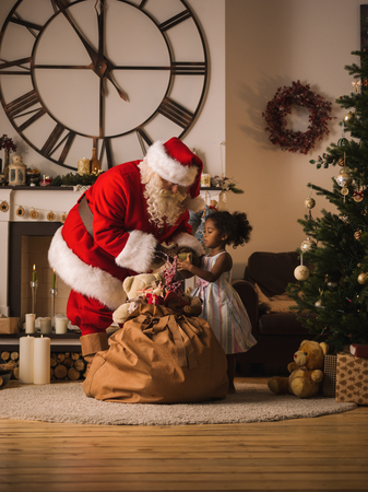 Santa Claus with Child at Home. Presenting Christmas Gifts from his Sackの写真素材