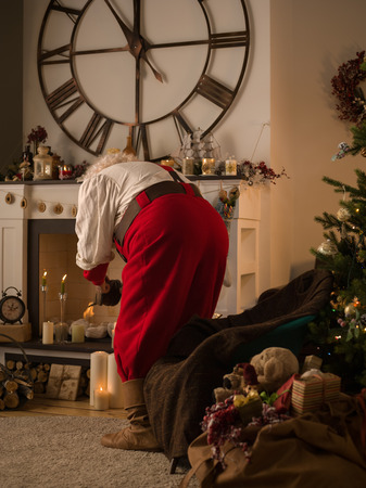 Santa Claus making Fire in Fireplace at Homeの写真素材
