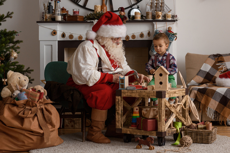Santa Claus with Child making Christmas Gifts and Toys at Homeの写真素材