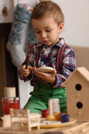 Cute little child painting wooden toys and decorations for Christmasの写真素材