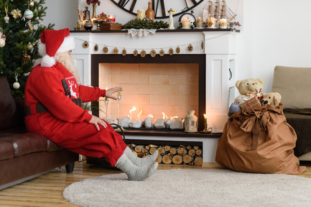 Santa Claus Warming near Fireplace at Homeの写真素材