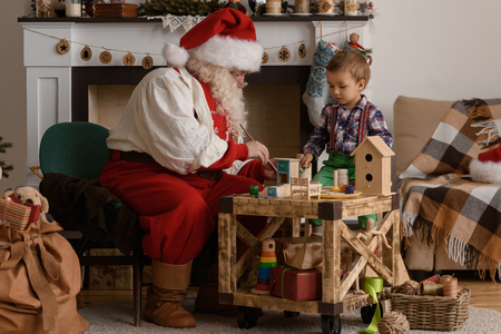 Santa Claus with Child making Christmas Gifts and Toys at Homeの写真素材