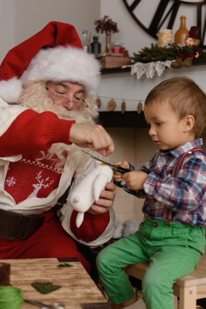 Santa Claus with Child sewing together at Homeの写真素材