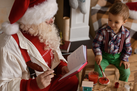 Santa Claus with Child making Christmas Gifts and Toys at Homeの写真素材