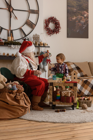 Santa Claus with Child making Christmas Gifts and Toys at Homeの写真素材