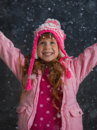 Little girl having fun under snow outsideの写真素材