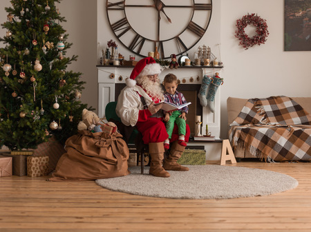 Santa Claus with Child Reading Book at Homeの写真素材