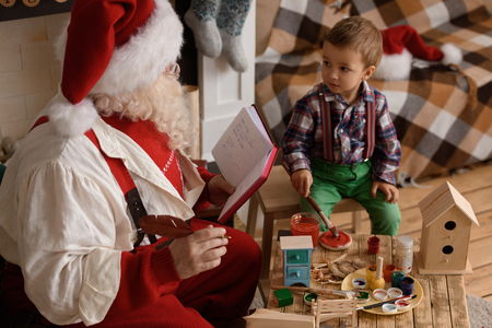 Santa Claus with Child making Christmas Gifts and Toys at Homeの写真素材