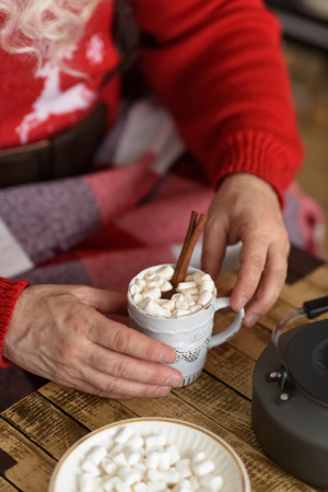 Santa Claus Drinking Coffee with Marshmallow near Fireplace at Homeの写真素材