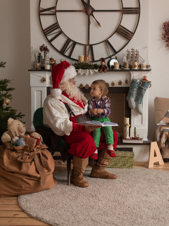 Santa Claus with Child Reading Book at Homeの写真素材