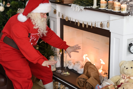 Santa Claus Warming near Fireplace at Homeの写真素材