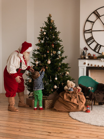 Santa Claus with Child Decorating Christmas Tree at Homeの写真素材