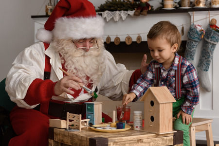 Santa Claus with Child making Christmas Gifts and Toys at Homeの写真素材