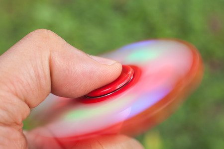 hand playing with fidget spinners stress relieving toy with running led on green background.Motion Blur due to Slow Shutter Shotの写真素材