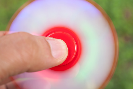 hand playing with fidget spinners stress relieving toy with running led on green background.Motion Blur due to Slow Shutter Shotの写真素材