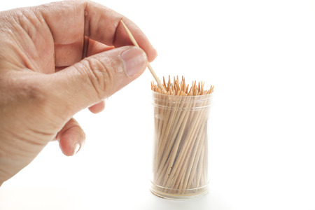 hand pick one wooden toothpicks from plastic container over white backgroundの写真素材
