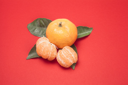 two orange tangerine or Mineola with slices and leaf on red backgroundの写真素材