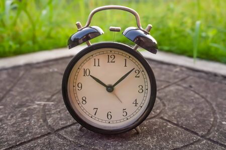 black analog clock over blurry green background