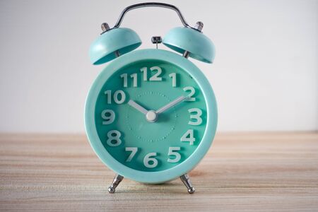 lite blue analog clock on wooden table