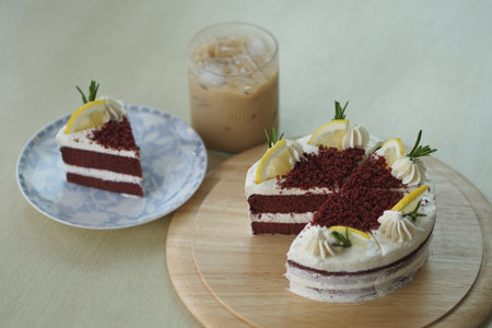 Red velvet cake with lemon and ice coffee on wood plate, vintage tone