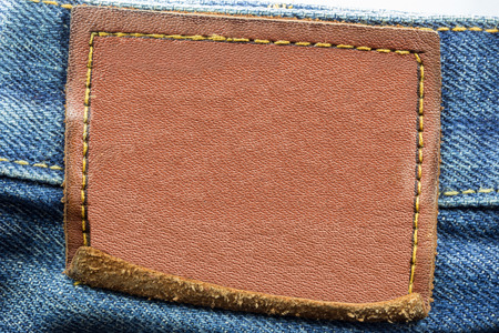 Blank leather jeans label sewed on a blue jeans isolated on white background
