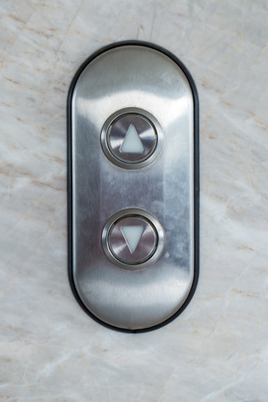 Gray Elevator Button up and down direction on marble wallの写真素材