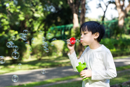 Asian little boy is blowing a soap bubbles in parkの写真素材