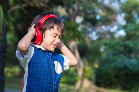 Little boy listening the music with headset in park
