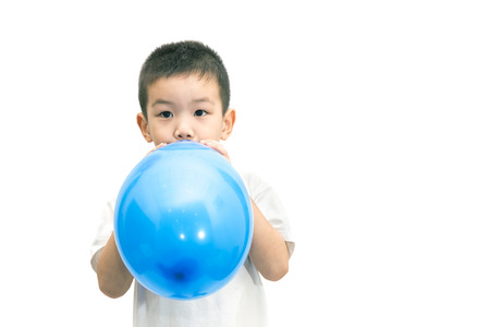 Little asian boy blowing a blue balloon isolated on white backgroundの写真素材