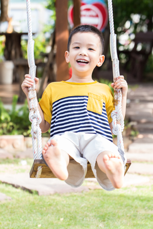 Asian baby boy playing on a swing and having fun in parkの写真素材