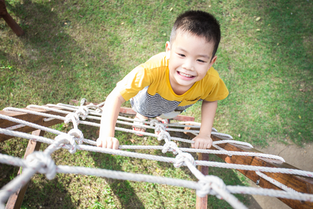 Little asian boy climbing rope obstacle activity on the playgroundの写真素材