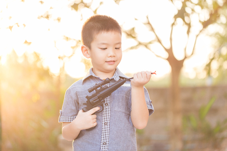 little asian boy playing with a toy gunの写真素材