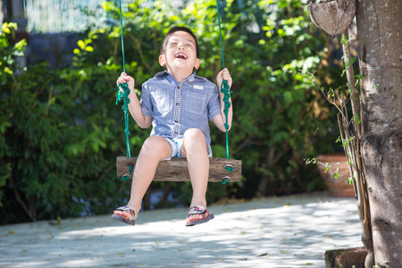Asian baby boy playing on a swing and having fun in parkの写真素材