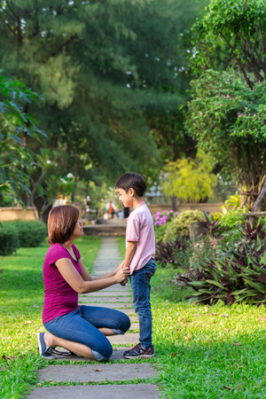 Mother sitting at park holding hands and teaching her sonの写真素材