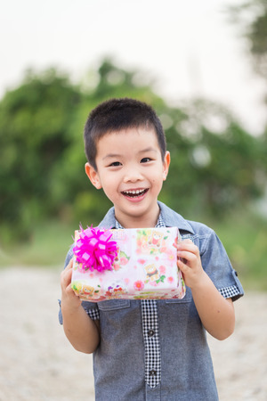 Asian child holding Christmas gift box in hand with smiling faceの写真素材