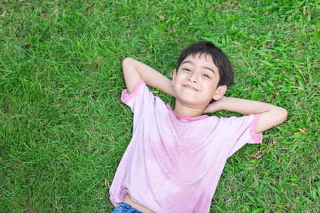 Little boy lay down on the grass with smile faceの写真素材