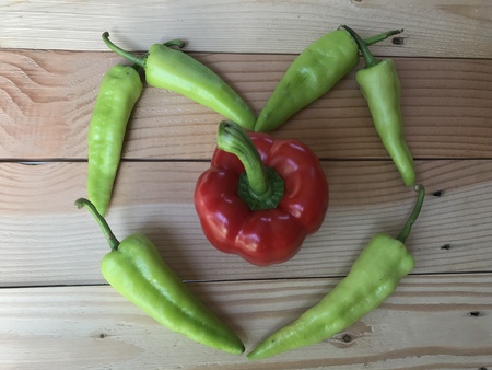 green chili peppers and red giant bell peppers made in heart shape on light brown natural color...
