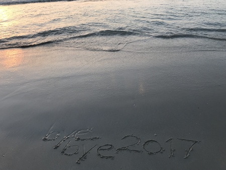 handwritten words âbye bye 2017â on the beach with sea waving when sunset, âfarewell year 2017â and âhappy new year 2018â conceptの写真素材