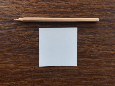 natural brown wood pencil and white blank paper in square shape putting in the middle of dark brown wood table, âgetting ideaâ conceptの写真素材