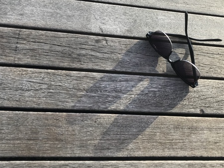 sunglasses and its shadow shine on natural color wooden bridge, taken by smartphoneの写真素材