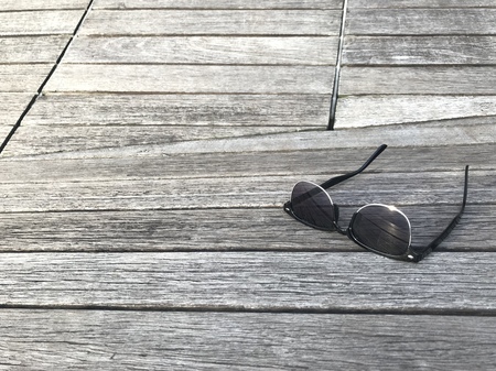 sunglasses put on stylish natural color wooden panel bridge with copy space, taken by smartphone