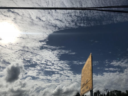 urban area and reduce speed warning sign beside road with electricity lines and bright sunshine and blue skyの写真素材