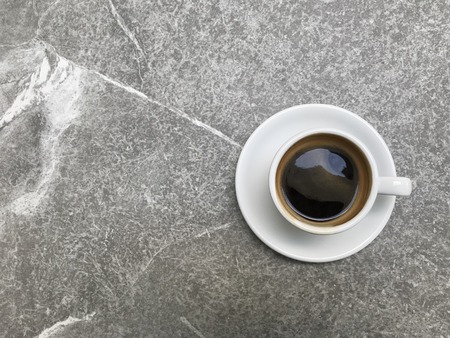 top shot of hot black coffee in white cup with saucer on grey marble table with copy space on left side of frameの写真素材